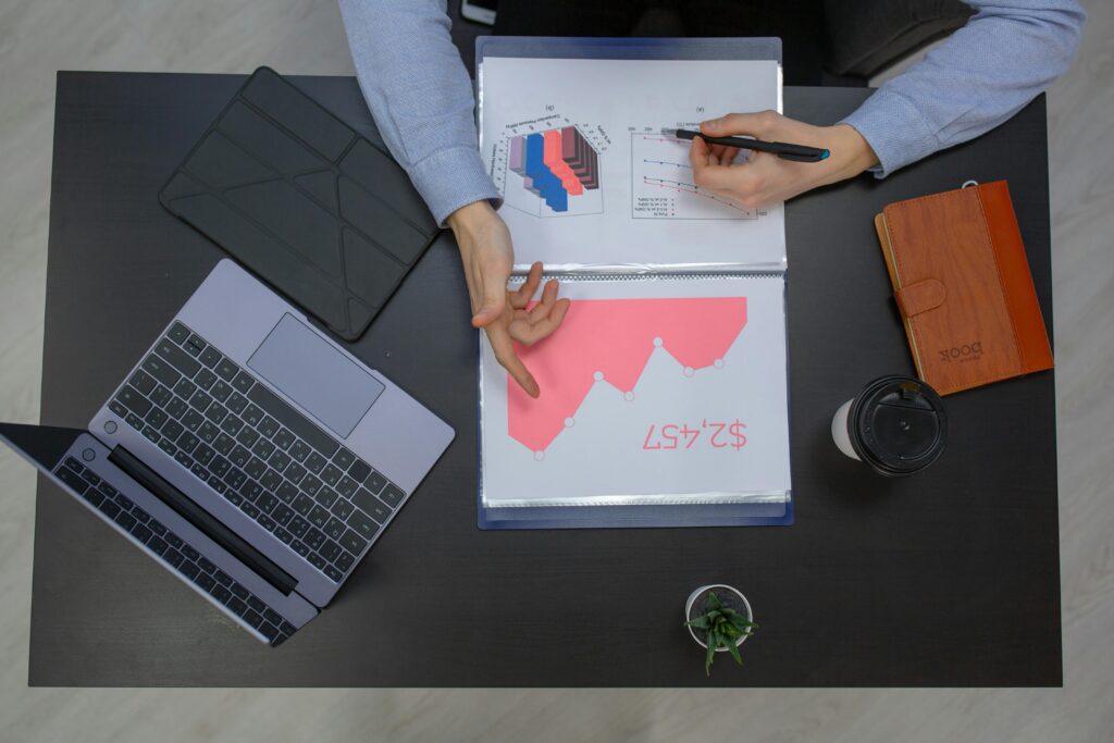 Business professionals discussing financial graphs at a desk with laptop and documents.