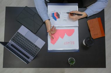 Business professionals discussing financial graphs at a desk with laptop and documents.